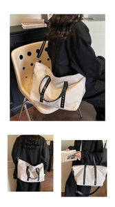 Detail of white tote bag featuring black studded handles and adjustable shoulder strap