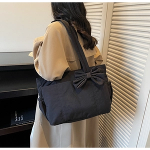 Détail d'un grand sac fourre-tout noir avec nœud décoratif et poche latérale pratique