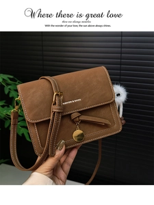 Detail of vintage brown leather handbag with contrast stitching and furry monster charm