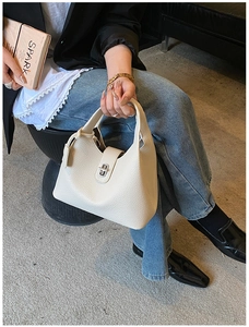 Detail of off-white lychee pattern leather bucket bag with silver metal twist lock clasp