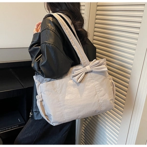 Detail of grey nylon tote bag showing bow decoration and side drawstring pocket