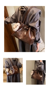 Détail d'un sac cabas vintage marron foncé avec un pendentif peluche et bandoulière
