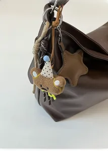 Détail d'un pendentif ours en peluche marron avec chapeau de fête sur un sac à main