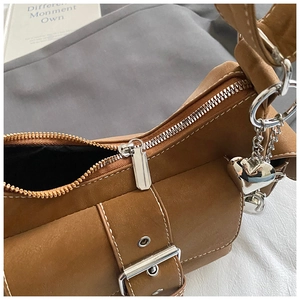Detail of silver zipper and heart pendant on a vintage brown shoulder bag