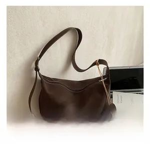 Close-up of coffee brown suede hobo tote bag featuring white stitching and round charm