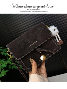 Detail of vintage brown crossbody bag with contrast stitching and plush charm