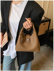 Detail of brown lychee leather handbag with silver metallic twist lock and elegant texture