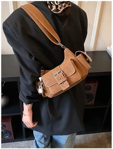 Close-up of brown suede shoulder bag with silver buckle and metallic lock pendant details
