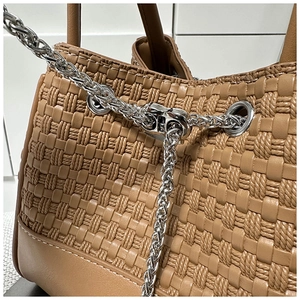 Detail of woven brown PU leather handbag with embossed texture and silver chain strap
