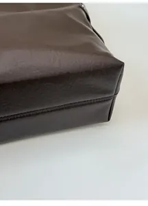Détail du fond large du sac cabas marron montrant les bords en cuir structuré et la forme