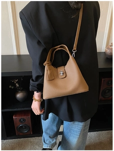 Rear view of model wearing a brown lychee leather bucket bag with silver twist lock