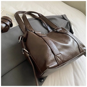 Detail of dark brown oil-wax tote bag with adjustable strap and vintage texture