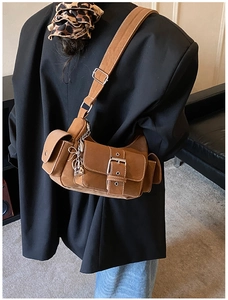 Detail of dark brown suede crossbody bag featuring silver metal buckles and chain straps