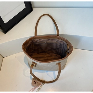 Spacious tote bag interior view with striped lining, zipper pocket and brown bear charm