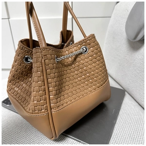 Detail of brown woven texture bucket bag with metal chain drawstring and dual handles