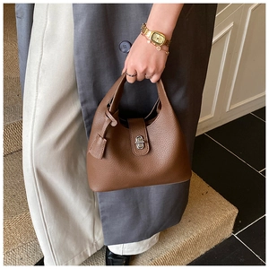 Detail of dark brown lychee leather handbag featuring a polished silver twist lock closure