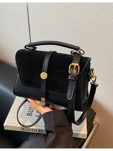Minimalist black matte crossbody bag with top handle and gold vintage buckle details