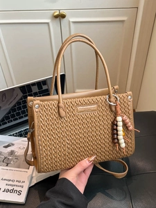 Brown embossed bucket bag with double handles and decorative beads on leather surface