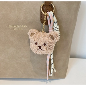 Close-up of plush bear charm with woven ropes on a retro shoulder bag handle