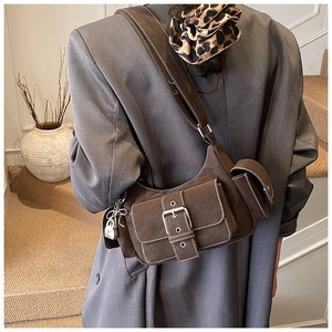 Detail of dark brown baguette bag with white contrast stitching and silver lock charm