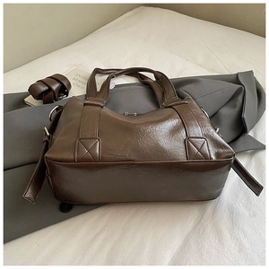Detail of dark brown tote bag showing leather texture, handle and metal hardware
