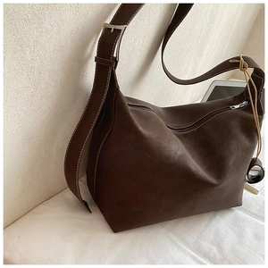Detailed view of dark brown suede tote with white contrast stitching and adjustable strap