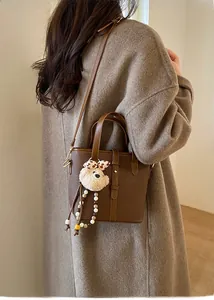 Detailed texture of brown lychee grain leather bucket bag with cute bear charm