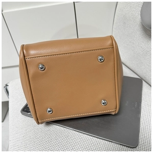 Detail view of the caramel leather bucket bag base with four silver metal feet and stitching