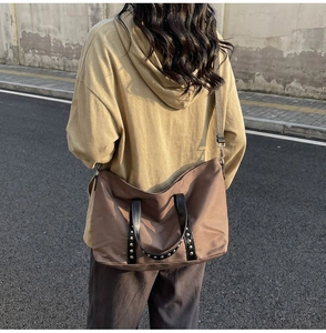 Sac cabas marron avec poignées à rivets porté à l'épaule pour un style quotidien