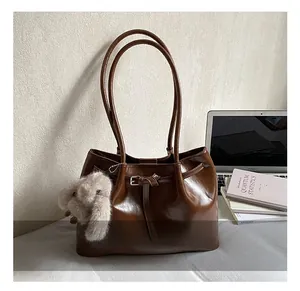 Détail du sac cabas en cuir marron foncé avec longues anses et breloque lapin en peluche