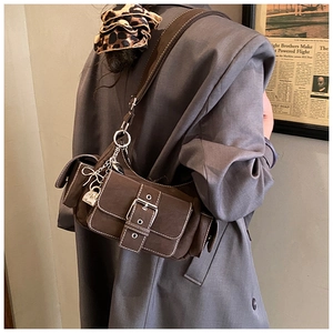 Detail of vintage brown suede crossbody bag featuring a large silver buckle and chain