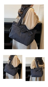 Detail of large black tote bag featuring a stylish oversized side bow and wide shoulder strap