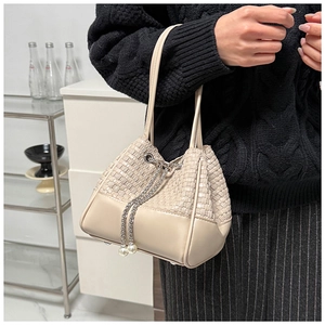 Close-up of woven cream bucket bag with elegant pearl-beaded drawstring metal chain