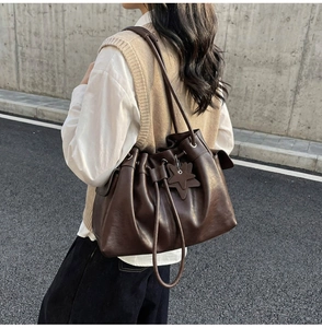 Detail of dark brown leather bucket bag featuring a drawstring closure and star charm