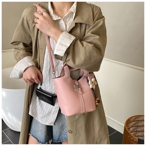 Pink lychee grain leather bucket bag with silver buckle and white floral charm on a model
