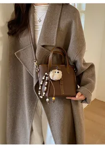 Detail of dark brown litchi pattern bucket bag with plush doll and beaded charm