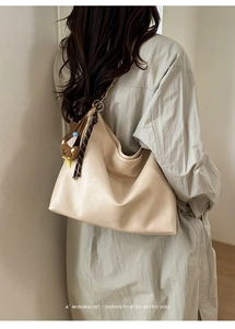 Gros plan du sac cabas beige en cuir grainé avec un charm d'ours et une texture souple