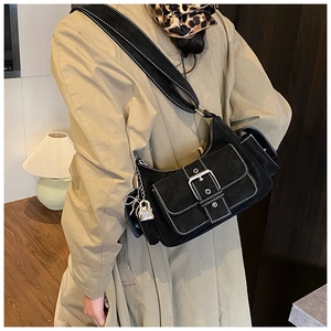 Close-up of black suede baguette bag with large metal buckle and silver lock details