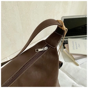 Detail of dark brown faux leather tote with contrast stitching and silver zipper closure