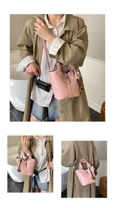 Pink lychee grain leather bucket bag with top handles and floral charm detail