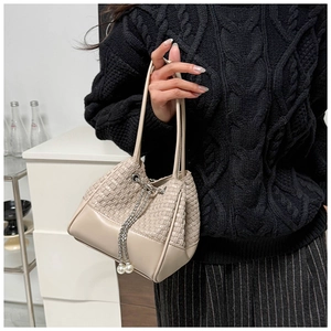 Close-up of woven bucket bag featuring elegant pearl drawstring and silver chain detail