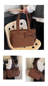 Detail of brown quilted tote bag with large bow and side pockets on a model