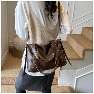 Detail view of dark brown faux leather tote bag with silver hardware on a model