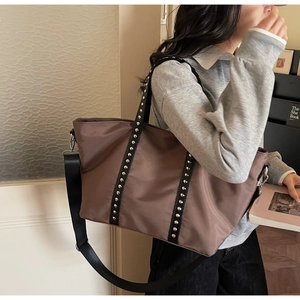 Détails du cabas en nylon marron avec lanières en cuir noir et rivets argentés