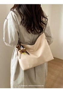 Vue arrière d'un grand sac hobo beige minimaliste avec un joli porte-clés ours en peluche
