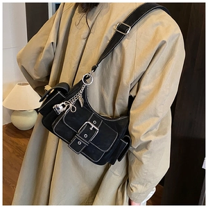 Detail of black crescent shoulder bag featuring white contrast stitching and heart chain