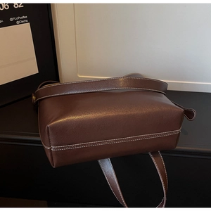 Close-up of vintage brown leather bucket bag showing white contrast stitching and texture