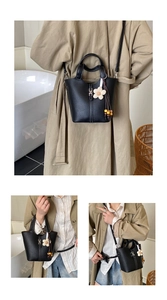 Detail of black lychee grain leather bucket bag with silver H-buckle and sunflower charm