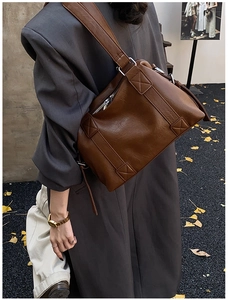 Close-up of retro brown leather Boston bag featuring reinforced cross stitching and wide strap