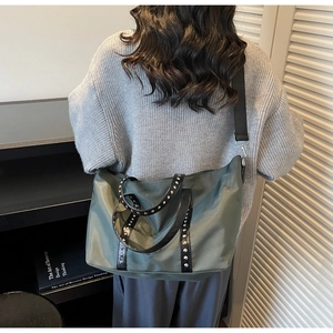 Detail view of large olive green tote bag featuring metallic rivets and wide strap